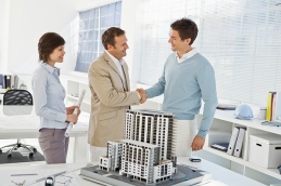 Architects shaking hands next to scale model
